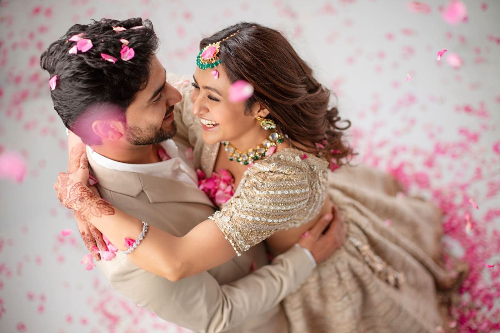 Couple embracing in a shower of pink petals