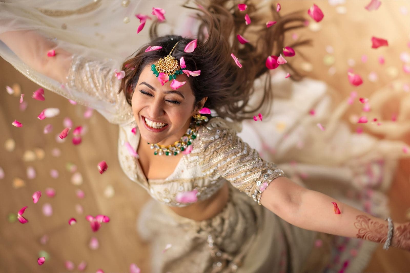 Bride laughing as rose petals fall around her