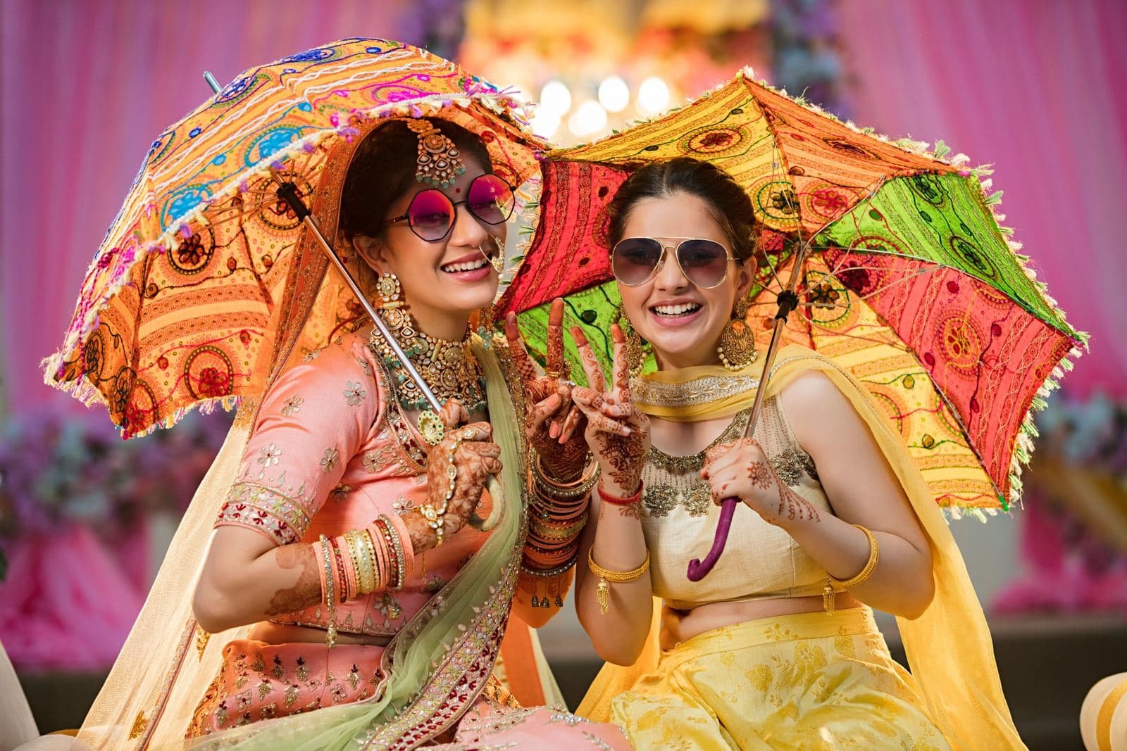 Friends celebrating at a haldi ceremony under colourful umbrellas