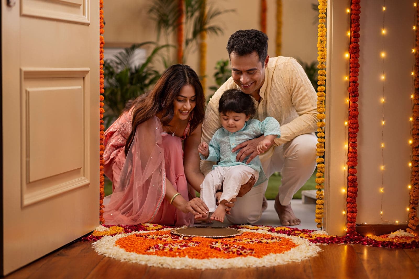 Family stepping into their new home over a rangoli