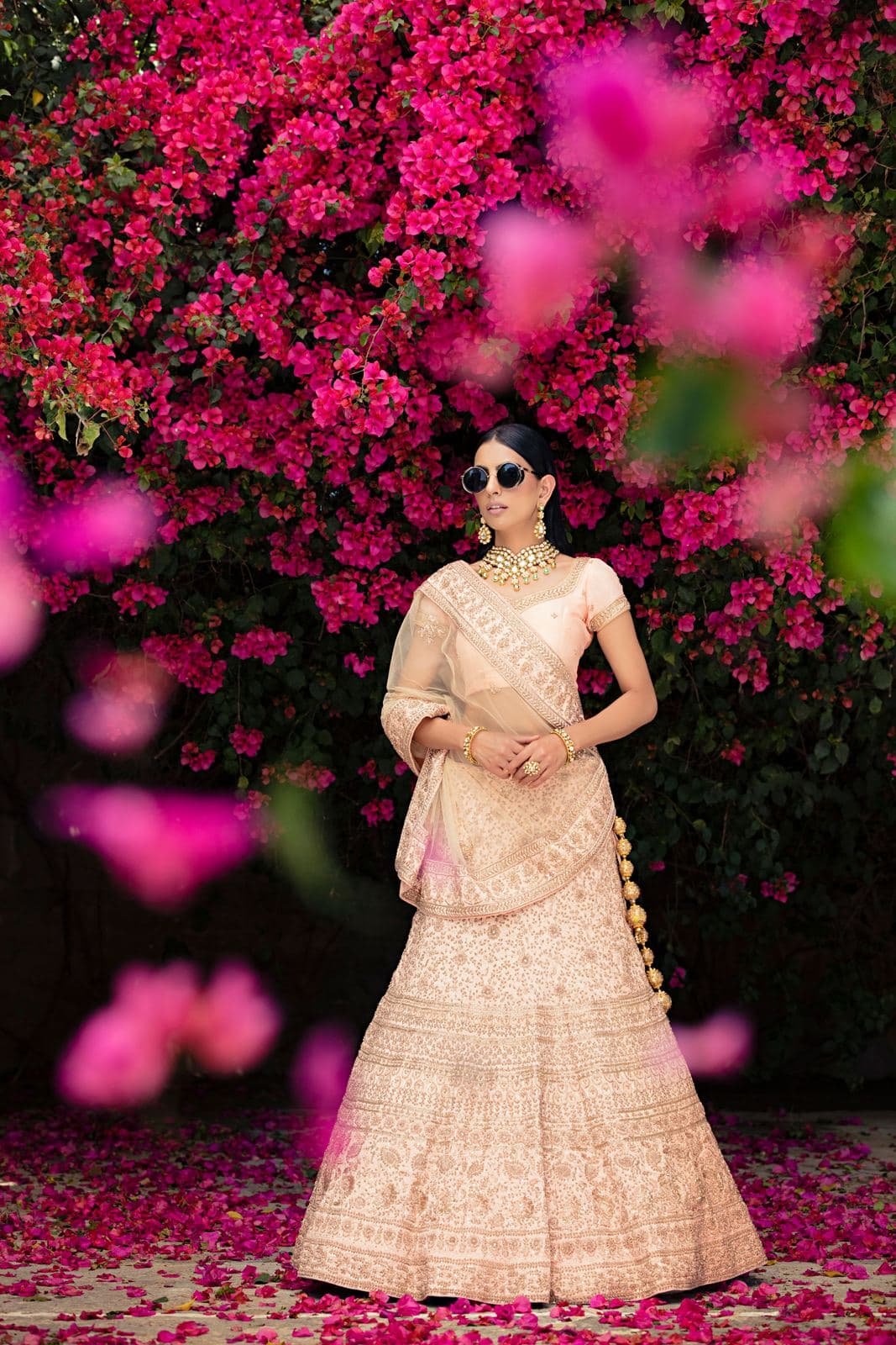 Woman in a pastel lehenga among bougainvillea flowers