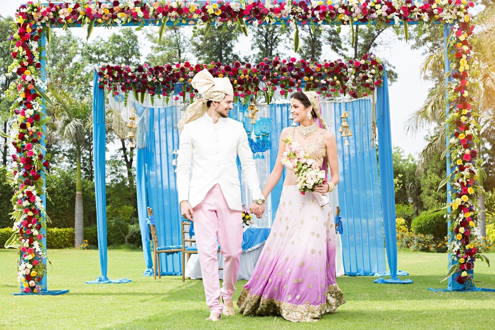 Couple walking under a floral arch on a garden lawn